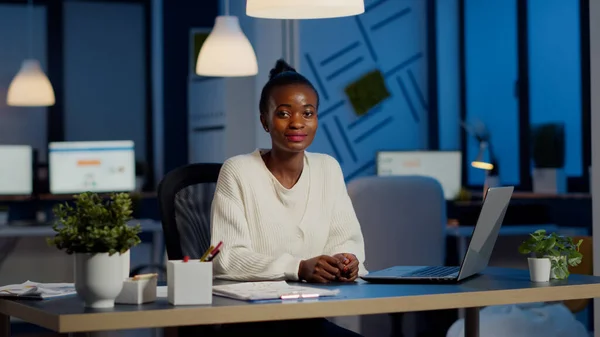 Mulher negra de negócios olhando para a câmera sorrindo levantando a cabeça do laptop — Fotografia de Stock