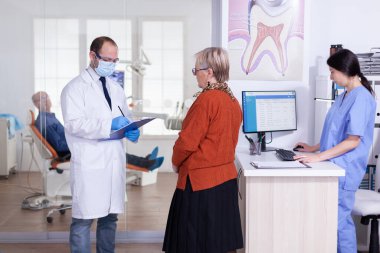Yüz maskeli dişçi doktor teşhisi açıklıyor.
