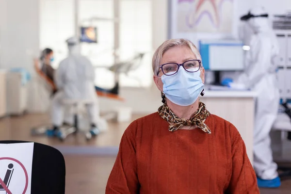 Mulher sênior na clínica dentária usando máscara facial — Fotografia de Stock