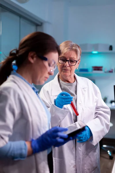 Químico senior que sostiene vacutainer con sangre y científico utilizando tableta pc vacuna de ingeniería — Foto de Stock