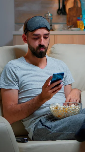 Unatkozó férfi ül a kanapén, kezében popcorn tál — Stock Fotó