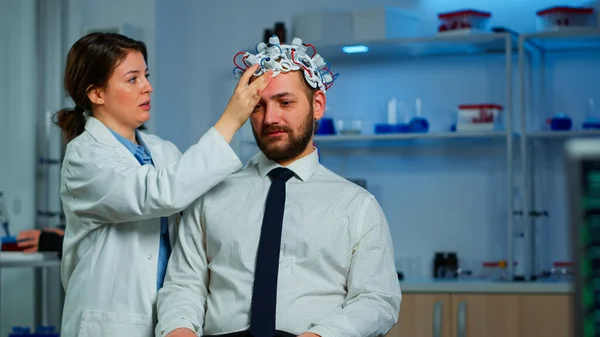 Médico neurólogo analizando el cerebro del hombre usando auriculares de escaneo de ondas cerebrales —  Fotos de Stock