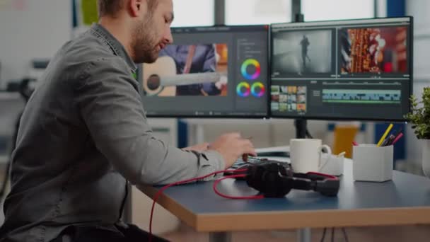 Videógrafo sonriendo a la cámara trabajando en el ordenador — Vídeo de stock