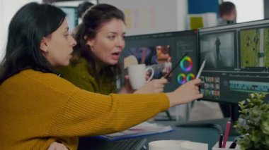 İş arkadaşları video düzenleyicileri müşteri görüntüleri için çalışan bilgisayar önünde tartışıyorlar