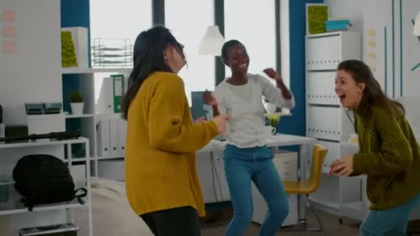 Смешанные гоночные счастливые женщины весело танцуют в офисе творческого агентства стартапа, — стоковое видео