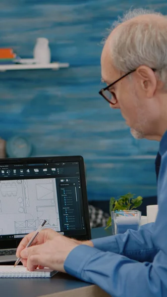 Senior man architecect analyzuje digitální prototyp s plány z notebooku — Stock fotografie
