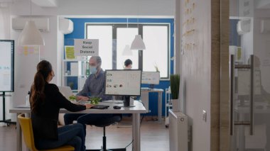 Yüzü maskeli bir iş adamı meslektaşıyla dirseğine dokunuyor.