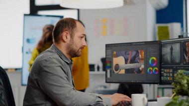 Video düzenleyicisi kameraya bakıyor, görüntülerle çalışıyor