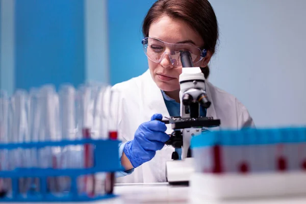 Mujer científica en bata blanca buscando en microscopio de gama alta — Foto de Stock