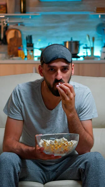 Hombre concentrado con máscara para dormir sentado frente a la televisión —  Fotos de Stock