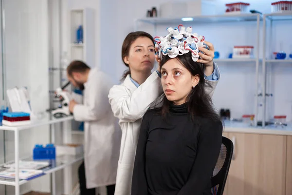 Woman wearing brain wave headset in modern medicine lab with neurologist doctor health physician