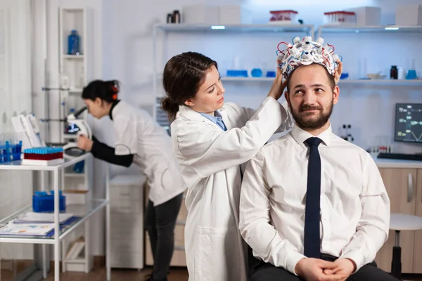 Une chercheuse met un casque de balayage d'ondes cérébrales à la patiente — Photo