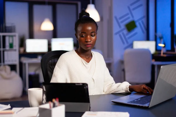 Donna d'affari africana oberata di lavoro che controlla i grafici su tablet pc — Foto Stock