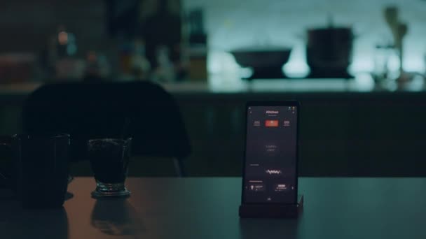 Умное домашнее приложение на телефон, расположенный на кухонном столе в пустом доме — стоковое видео