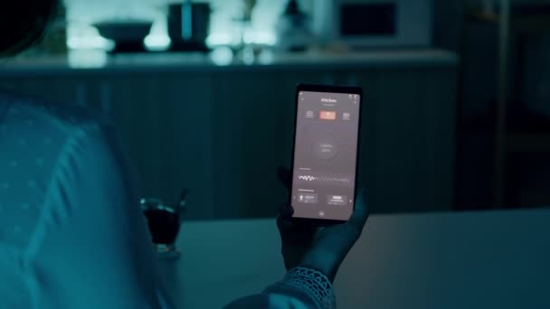 스마트폰을 들고 있는 자동화 조명 시스템을 가지고 집에 앉아 있는 여성 — 비디오