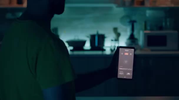 Mannelijke holding mobiel met verlichting controlerende app zitten in de keuken — Stockvideo