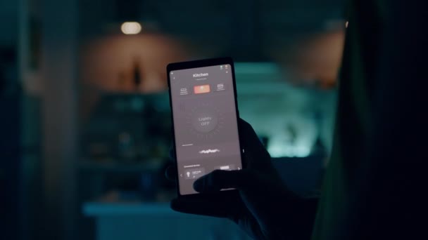 Человек, использующий смартфон со смарт-приложением безопасности дома, включающим свет — стоковое видео