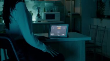 Otomasyon aydınlatma sistemi olan evde tablete bakan bir kadın