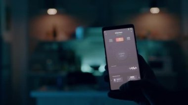 Akıllı evde çalışan erkek aydınlatma kontrol uygulaması olan cep telefonu kullanıyor