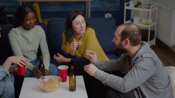 Amigos multiculturales socializando mientras están sentados en el sofá en la sala de estar tarde en la noche — Vídeos de Stock