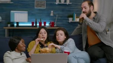 Çok ırklı arkadaşlar birlikte vakit geçirip eğlence filmi izliyorlar.