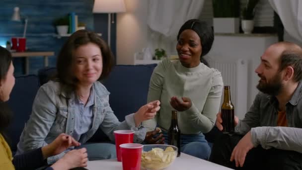 Amigos multiculturales riendo mientras comparten consejos de estilo de vida sentados en el sofá — Vídeos de Stock