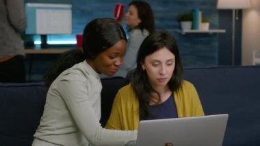 Dizüstü bilgisayarda komik videolar izlerken gülen çok ırklı arkadaşlar.