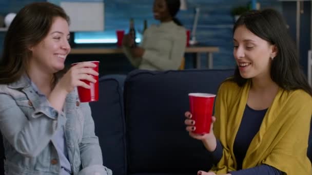 Dwie kobiety relaksujące się na kanapie pijące piwo podczas towarzyskiej imprezy — Wideo stockowe