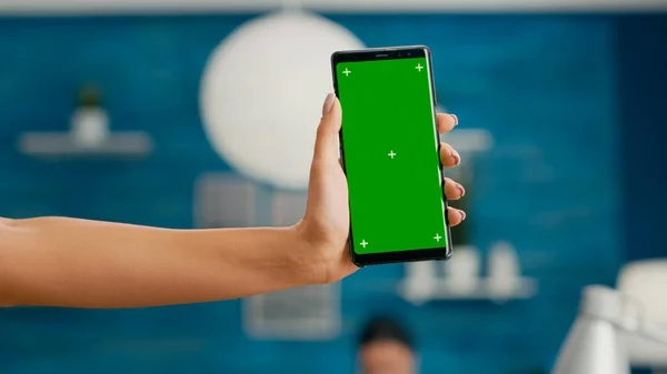 縦型モックアップを持つフリーランサーの手緑の画面クロマキースマートフォン — ストック写真