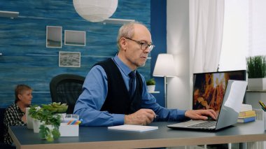 Ev bilgisayarında çalışan orta yaşlı bir işadamı not alıyor.