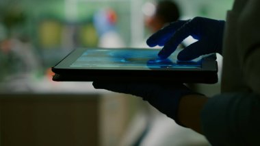 Kimyager kadın DNA örneğini tablet kullanarak kontrol ediyor.