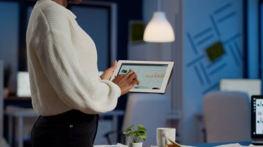 Afrikalı serbest çalışan kadın elinde tablet, mali grafikleri kontrol ediyor.