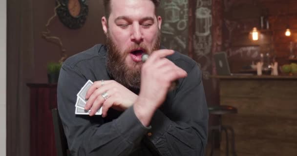 Mężczyzna pali elektronicznego papierosa i gra w karty — Wideo stockowe