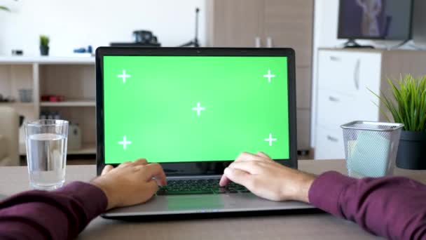 Manos masculinas escribiendo en el portátil con una maqueta de croma de pantalla verde en la sala de estar — Vídeos de Stock