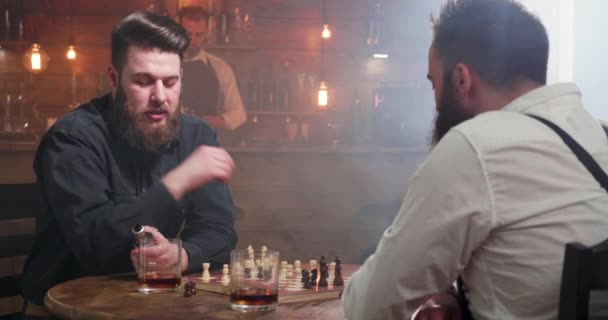 Mannelijke vrienden die een praatje maken tijdens een schaakspel — Stockvideo