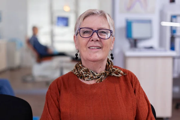 Elderly woman looking at camera in dental waiting room — Stock Photo, Image