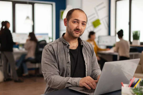 Hombre de negocios sentado en el escritorio mirando la cámara analizando las estadísticas financieras — Foto de Stock