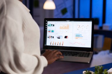 Koyu renk tenli iş kadınının dizüstü bilgisayarda yazmasını kapat.