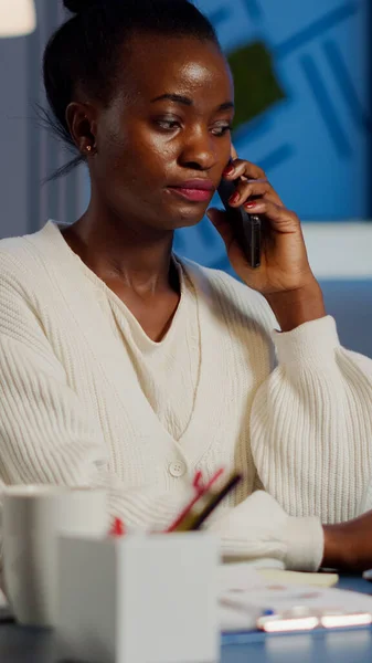 Employé africain parlant au téléphone tout en travaillant à l'ordinateur portable tard dans la nuit — Photo