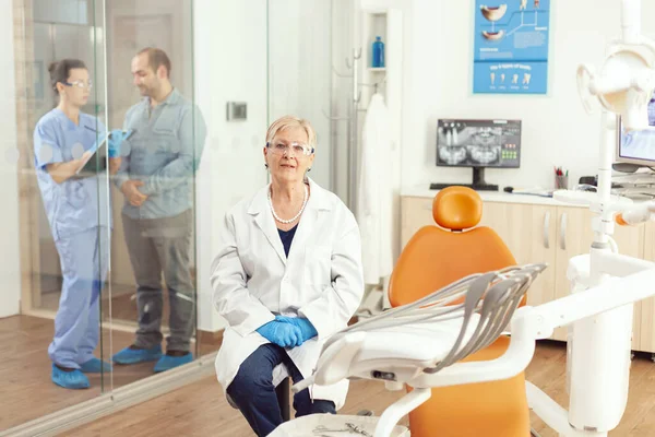 Portrait of senior dentist woman sitting on chair in stomatological hospital — Stock Photo, Image