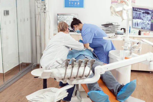 Больной человек сидит в стоматологическом кресле с открытым ртом для обследования — стоковое фото