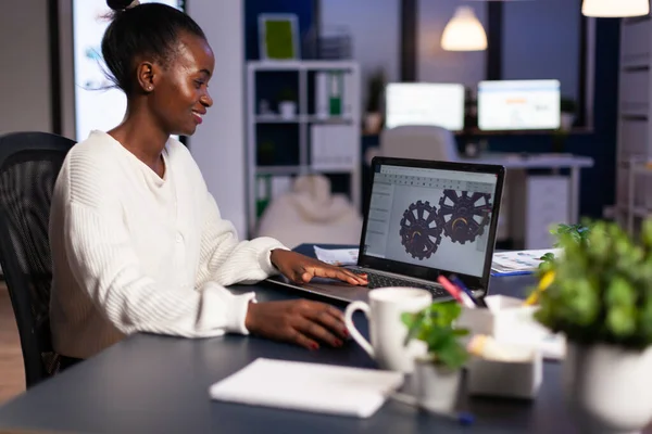 Diseñador mecánico africano trabajando en el ordenador tarde en la noche —  Fotos de Stock