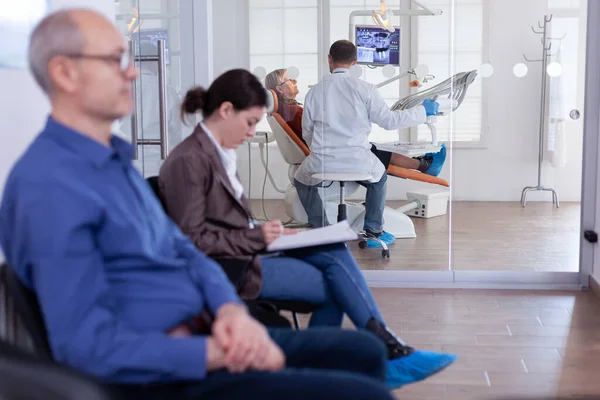 Femme âgée assise sur une chaise dans un cabinet dentaire dentiste à l'écoute — Photo