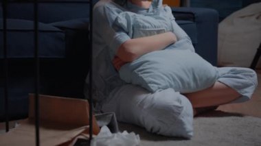 Siyahi bakışlı travma geçirmiş bir kadın yerde tek başına oturuyor.