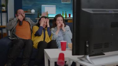 Çok ırklı arkadaşlar kanepede oturup televizyon seyrediyorlar.