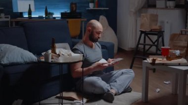 Çaresiz yetişkin bir adam yerde oturup gözyaşı dökme uyarısıyla kitap okuyor.