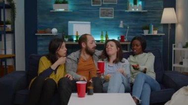 Çok ırklı arkadaşlar televizyondaki uzaktan kumandayı kullanarak kanal değiştiriyor