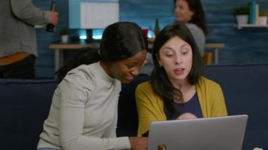 Çok ırklı arkadaşlar komedi videolarında kanepede dinlenirken abur cubur yiyorlar.