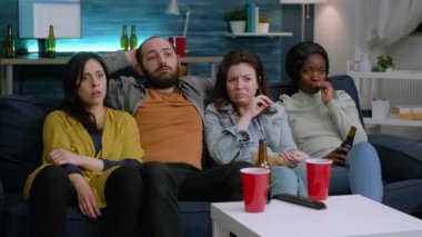 Çok ırklı korkmuş arkadaşlar televizyonda korku filmi izliyorlar.