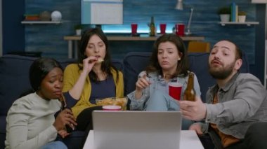 Kanepede oturup komedi filmi izleyen çok ırklı arkadaşlar.